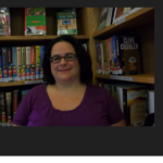 Kristin Jaques smiling in front of a library bookshelf.